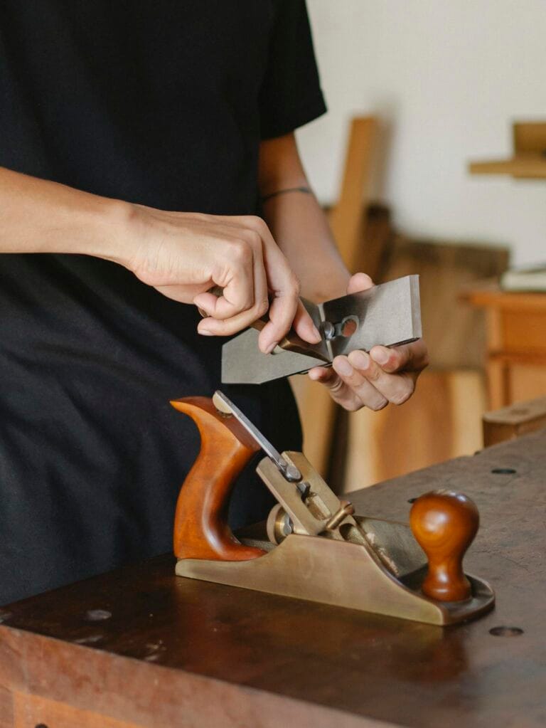 Close-up of a carpenter sharpening a tool on a workbench, highlighting artisanal craftsmanship.