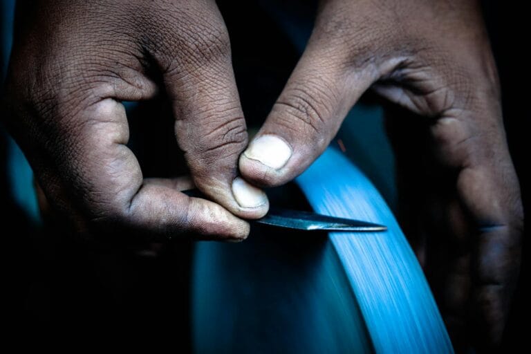 Focused close-up image of hands sharpening a knife wheel in Mumbai, India.