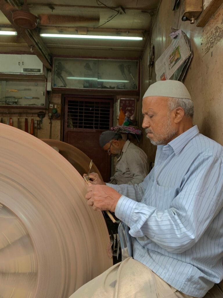 Two craftsmen sharpening knives in a traditional Pune workshop, focused on their craft.